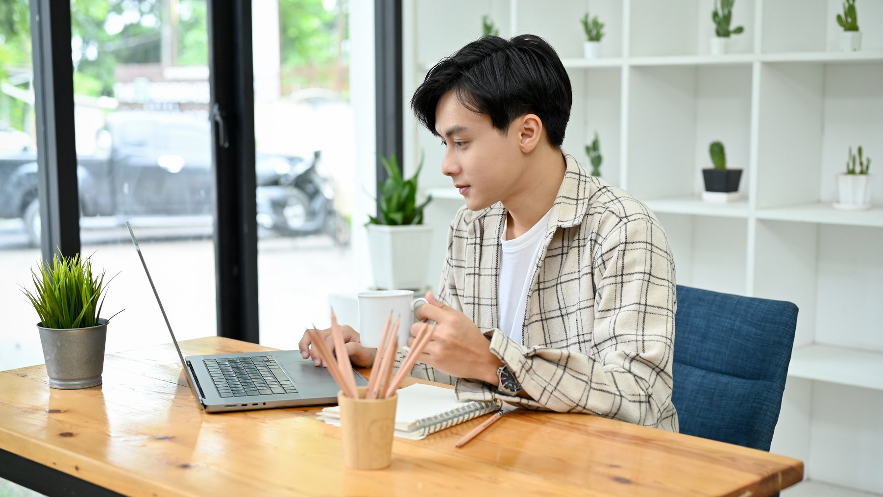 Smart and professional Asian male office employee using laptop w